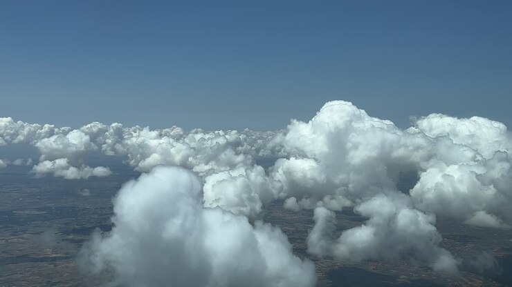 Flying across a sky with some white cumulus clouds, recorded from an airplane cabin
