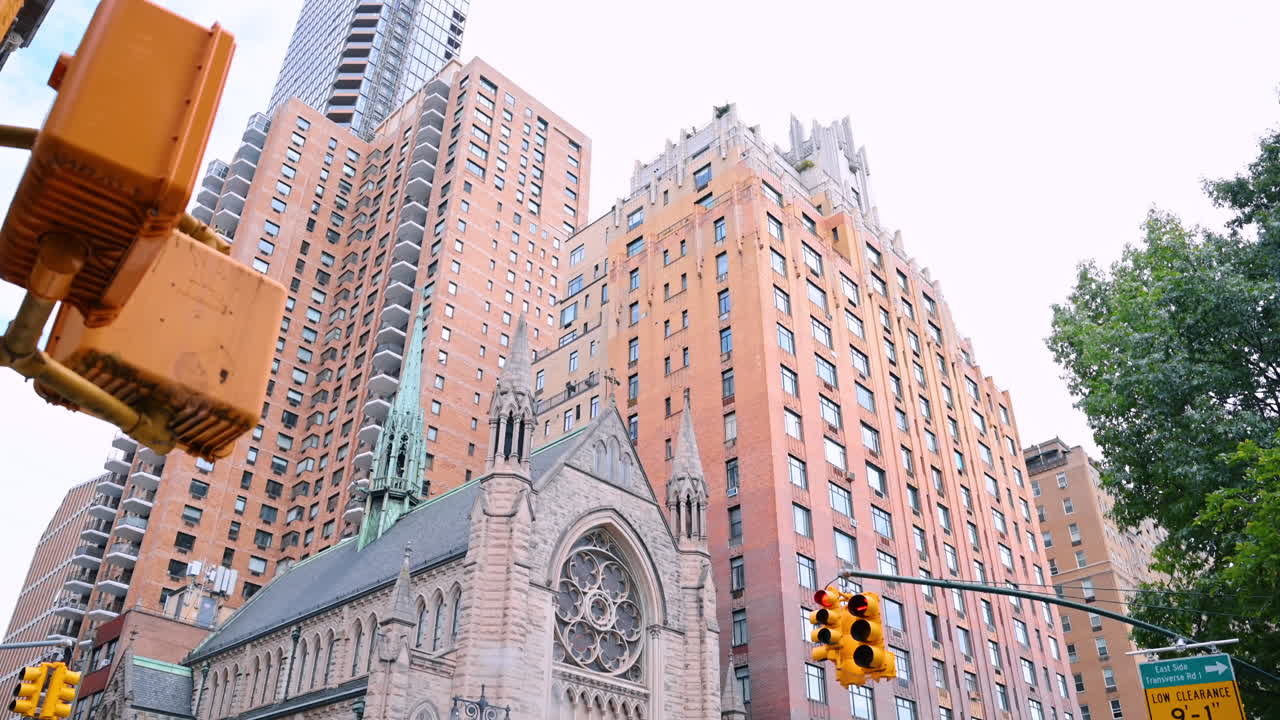 New York, USA, 8 luglio 2025: Chiesa cattolica romana della Santissima Trinità situata all'angolo della strada. Angolazione dal basso dell'edificio di molti piani vicino alla chiesa e al lampione giallo. New York, USA