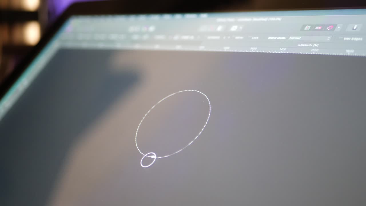 A freelance artist and creative designer sketching and painting shapes on a digital graphic tablet in a studio