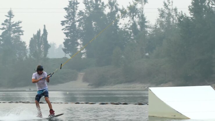 Front view of caucasian young man doing tricks on wakeboard in the city lake 4k