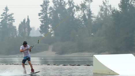 Vista-Frontal-De-Un-Joven-Caucásico-Haciendo-Trucos-En-Wakeboard-En-El-Lago-De-La-Ciudad-4k