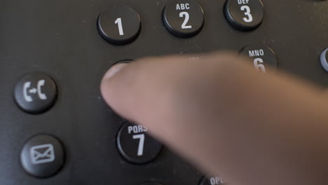 finger pressing buttons on landline telephone