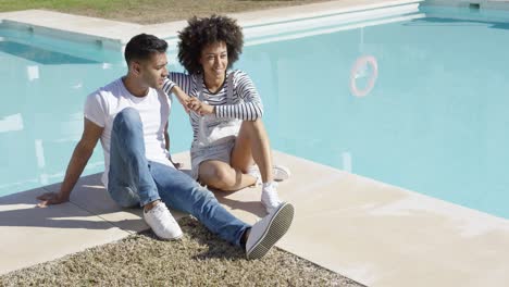 Mujer-Joven-Relajante-Con-Su-Novio-Junto-A-La-Piscina