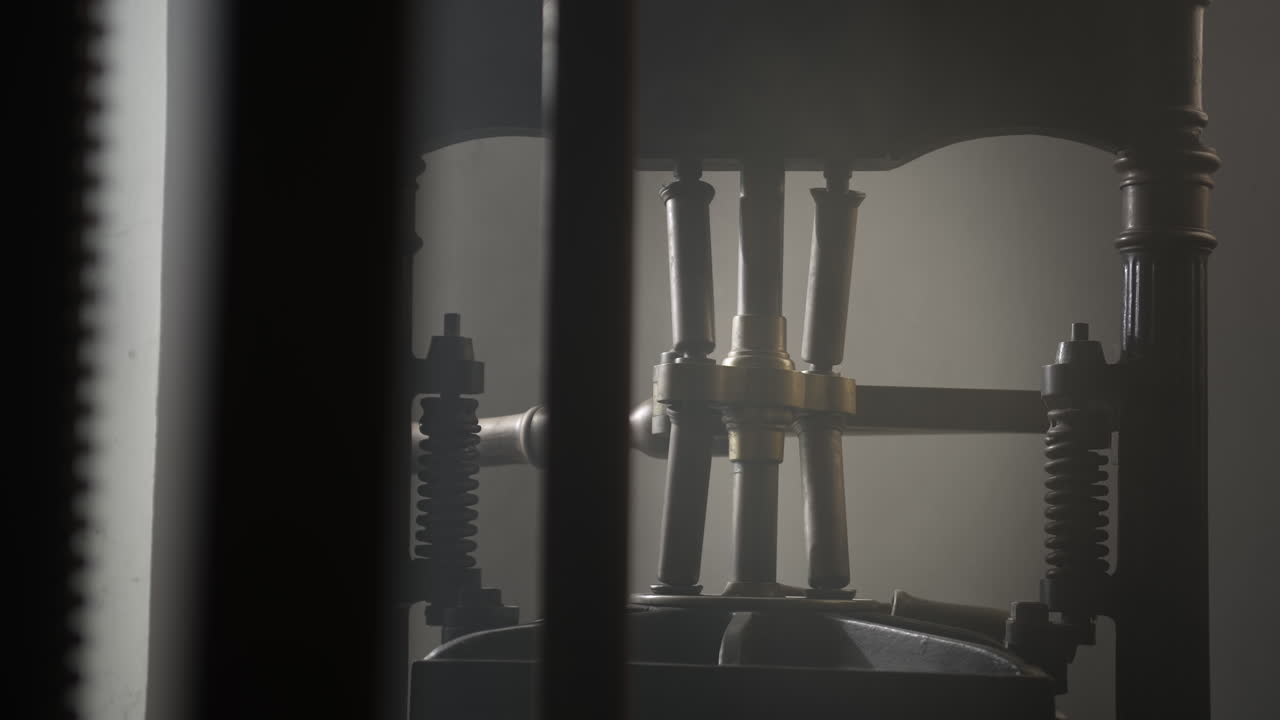 창문을 통해 들어오는 빛으로 불이 켜진 어두운 공간에 있는 오래된 인쇄기의 사진