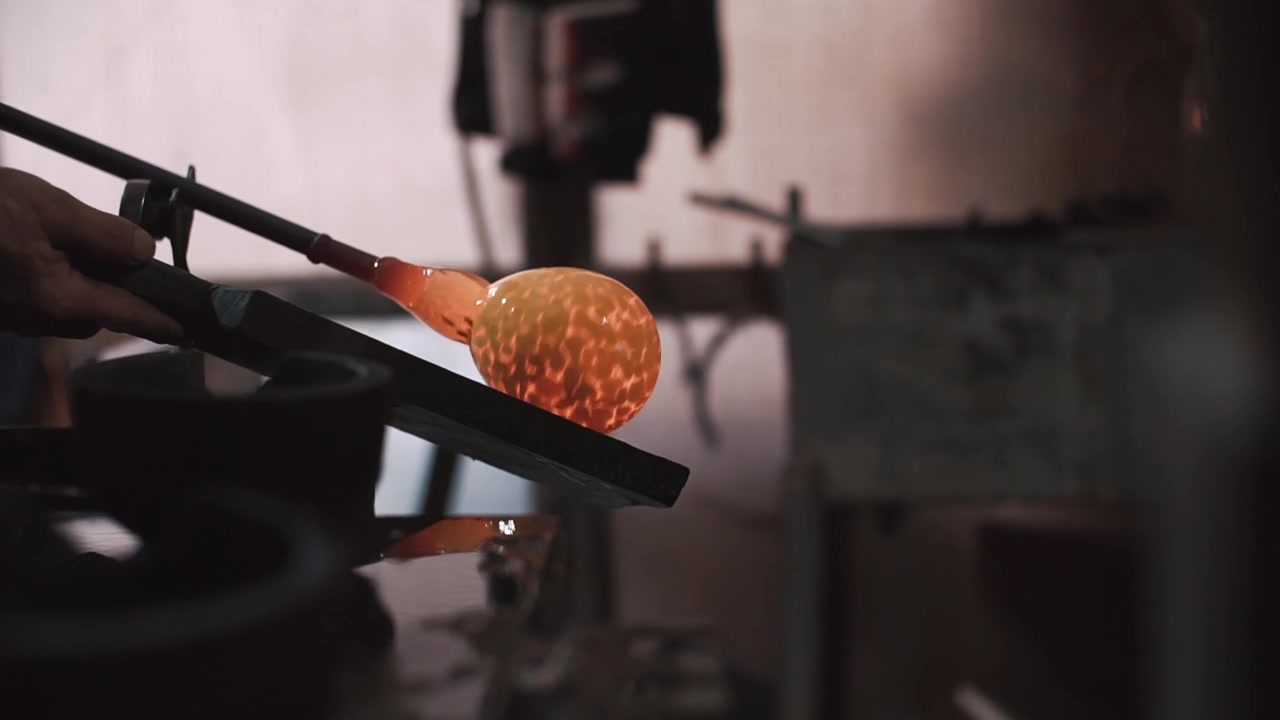 Artisan Carefully Shaping Hot Molten Glass in a Workshop