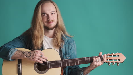 caucasian young man playing guitar on camera.