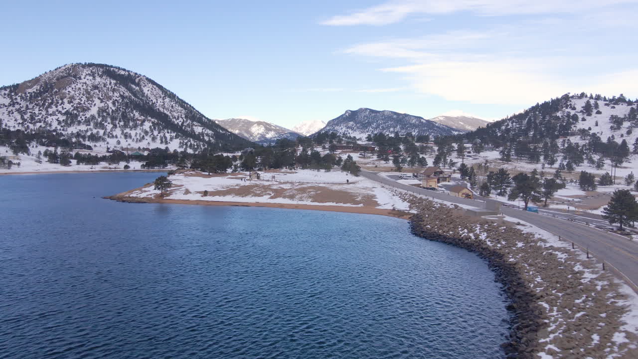 Aerial dolly over evergreen trees towards Grand Lake Colorado and mountain peaks
