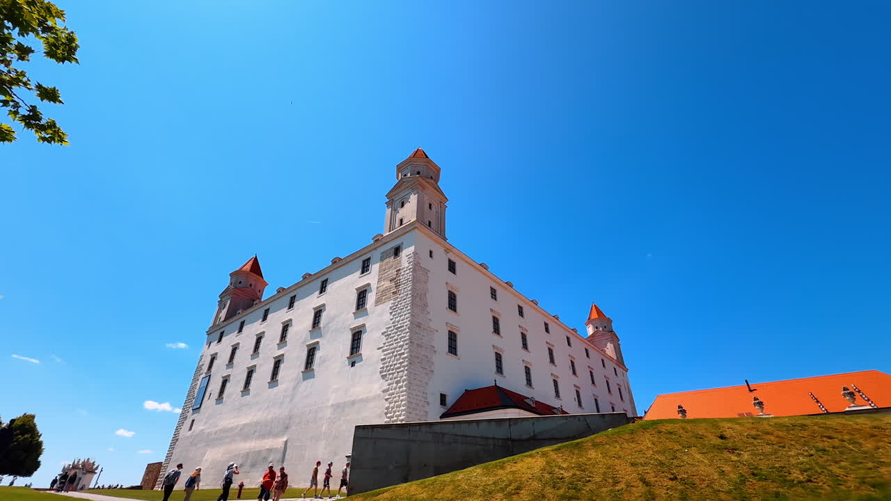 Walking up the hill to approach the Bratislava Castle. Low angle view at the white façade of the landmark at the backdrop of blue sky