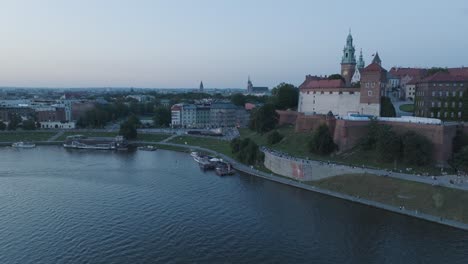 Toma-Aérea-De-Drones-Del-Casco-Antiguo-Del-Castillo-De-Wawel-En-Cracovia,-Polonia,-Con-El-Río-Vístula-Al-Amanecer.