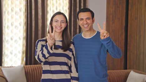 una feliz pareja india mostrando el signo de la victoria