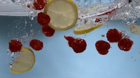 frambuesas y limones golpeando la superficie del agua