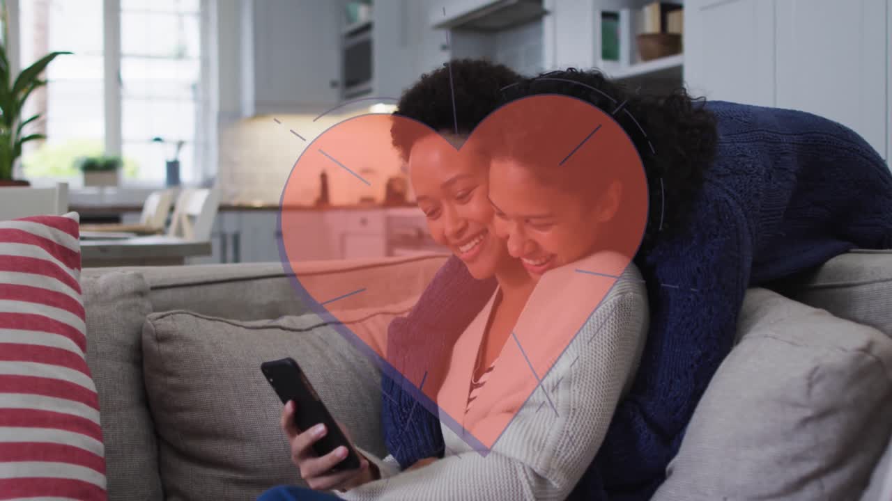 Animação de coração vermelho sobre duas mulheres usando smartphone