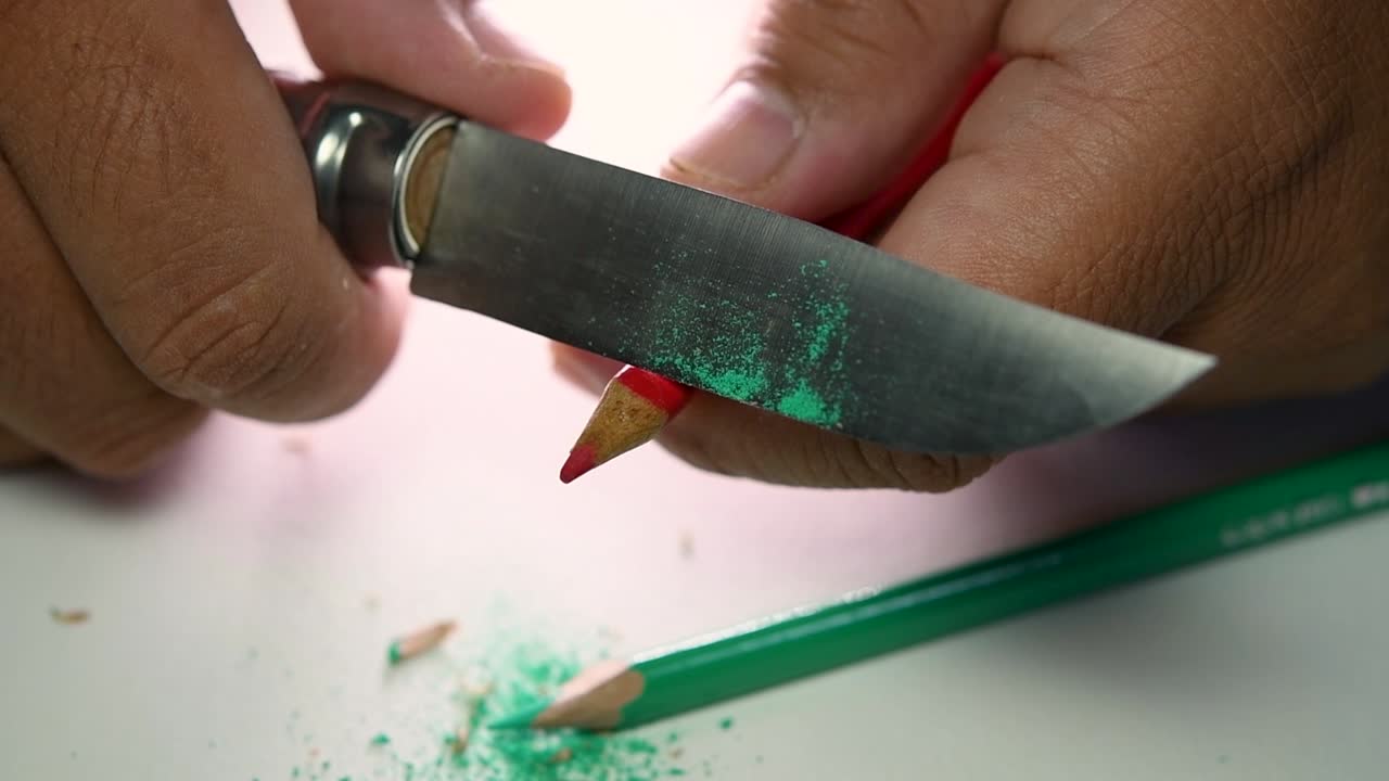 imágenes de manos afilando lentamente un lápiz y algunos lápices de colores con un cuchillo afilado