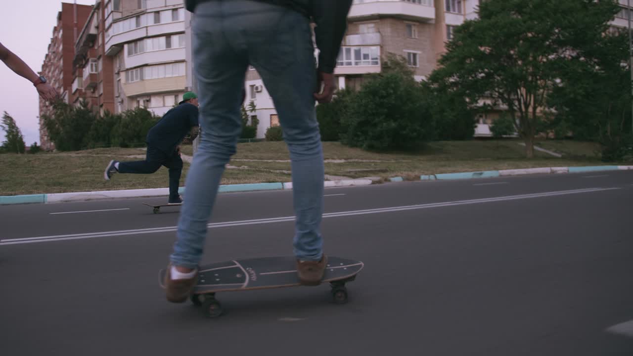 Gruppo di giovani che fanno skateboard sulla strada al mattino presto, ripresa cinematografica, slow motion.