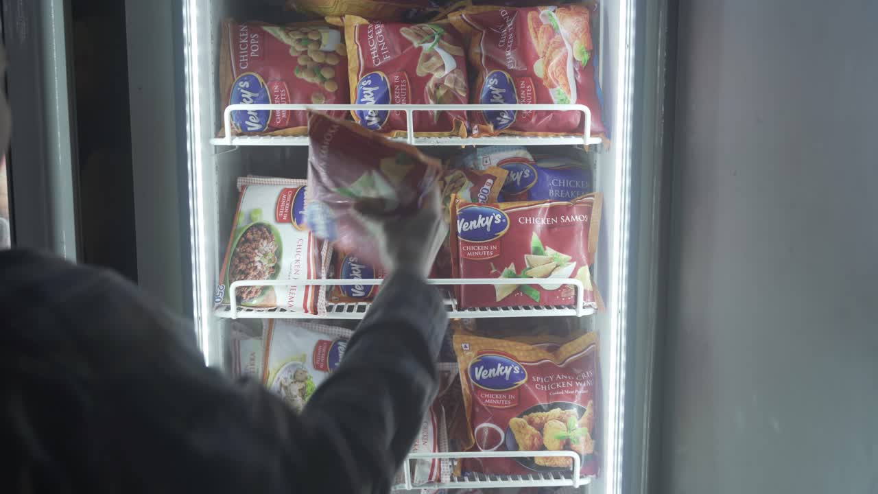 Customer picking frozen packaged and processed food from the refrigerator at a supermarket, Chicken samosa, Indian snacks
