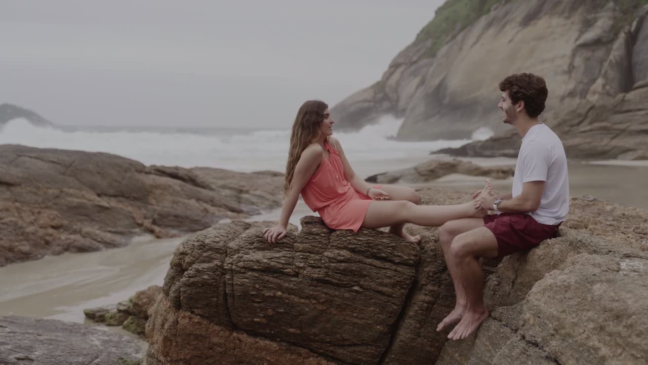 Couple relaxing with a foot massage on beach rocks