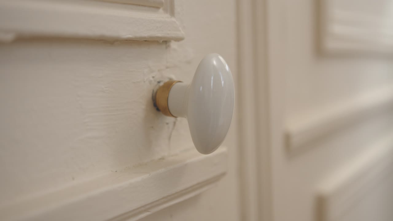 Woman's hand turning doorknob of old door