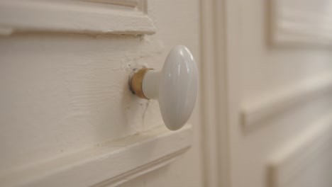 woman's hand turning doorknob of old door