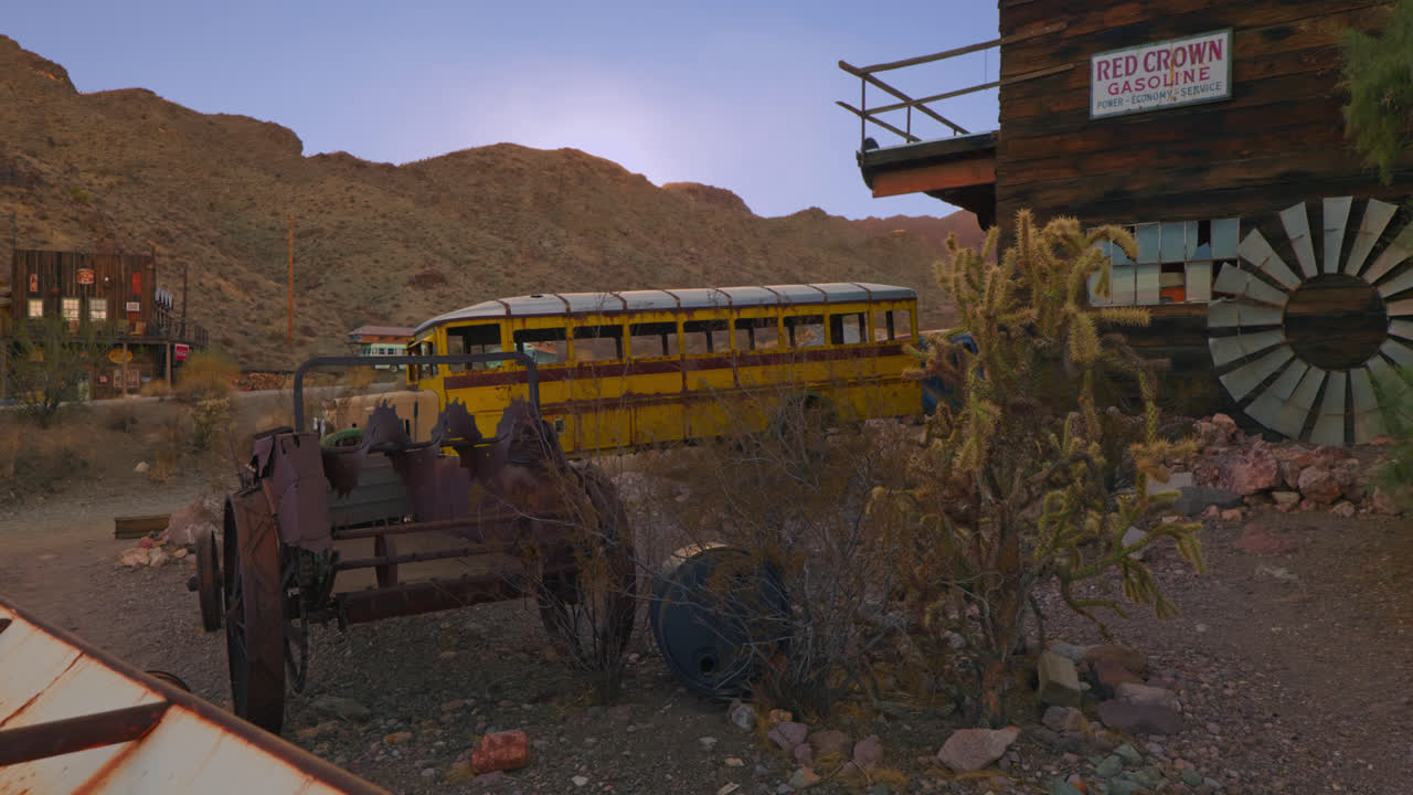 An Old School Bus and machinery sit abandoned in a old Ghost town.
