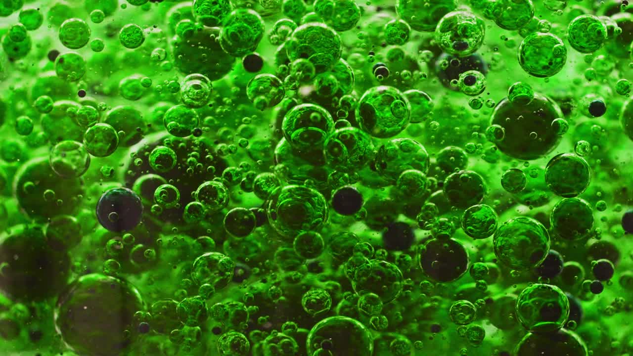 짙은 녹색 거품이 물에 섞이고 천천히 떠다니는 매크로 샷