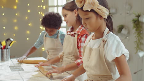 asian girl rolling dough on kids cooking class