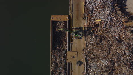 Aerial-birds-eye-overhead-top-down-descending-view-of-loading-metal-scrap-on-barge.-Recycle-and-ecology-concept.-New-York-City,-USA