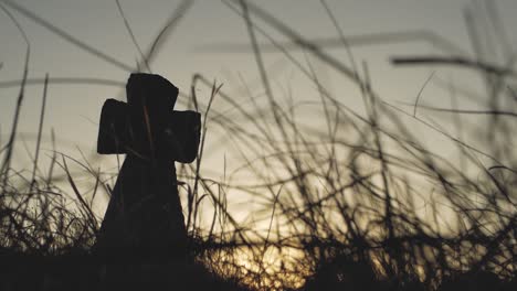 isolated stone cross silhouette in a grass field during sunset, inspiring catholic background for prayers