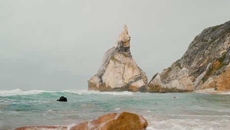 waves crashing on a rocky beach with a large sea stack