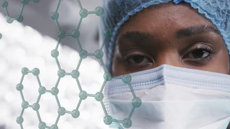 animation of element structure over african american female surgeon in cap and face mask