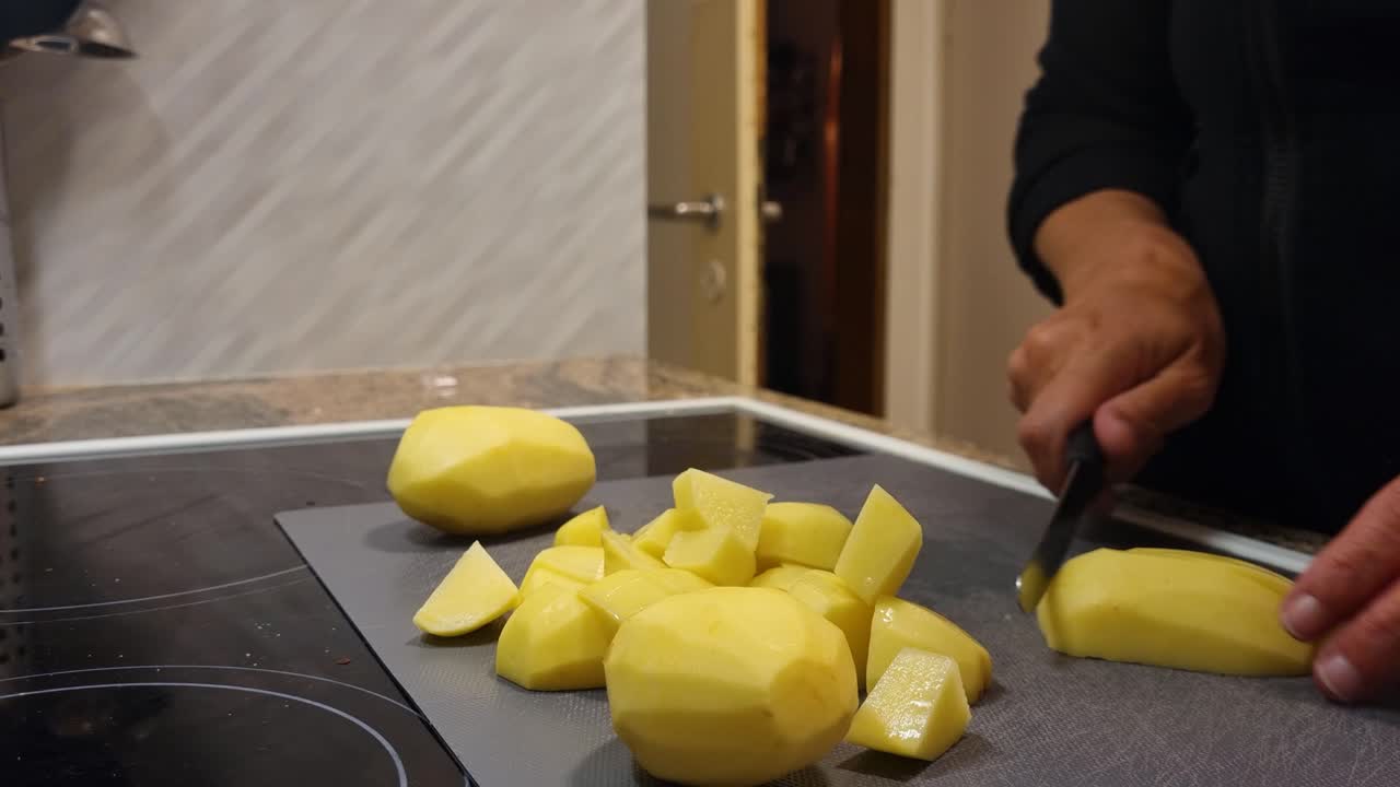 A woman’s hands cut potatoes into small pieces in a warm Swiss home kitchen, preparing a wholesome, affordable meal in a simple, homely setting