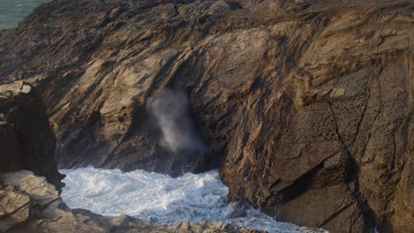 slow motion of waves crashing through dramatic blowhole in porth island, newquay, cornwall, uk