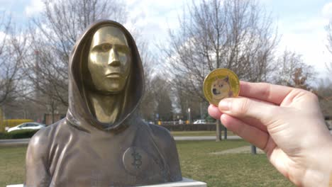 ficha dogecoin junto a la estatua de satoshi nakamoto