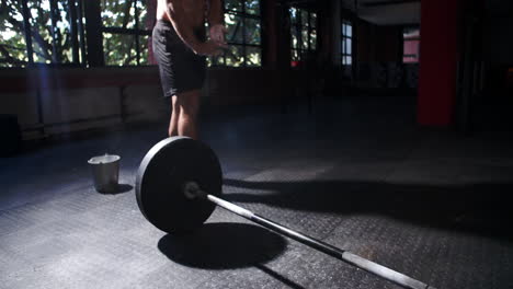 bare chested man weightlifting barbells in a gym