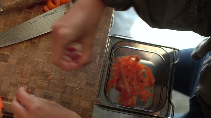 Close Up of Female Hands Discarding Carrot Offcuts into Bin