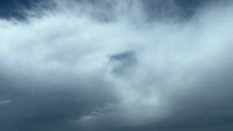A pilot&rsquo;s perspective shot from a jet cabin while flying through some fluffy clouds with a deep blue sky at the back