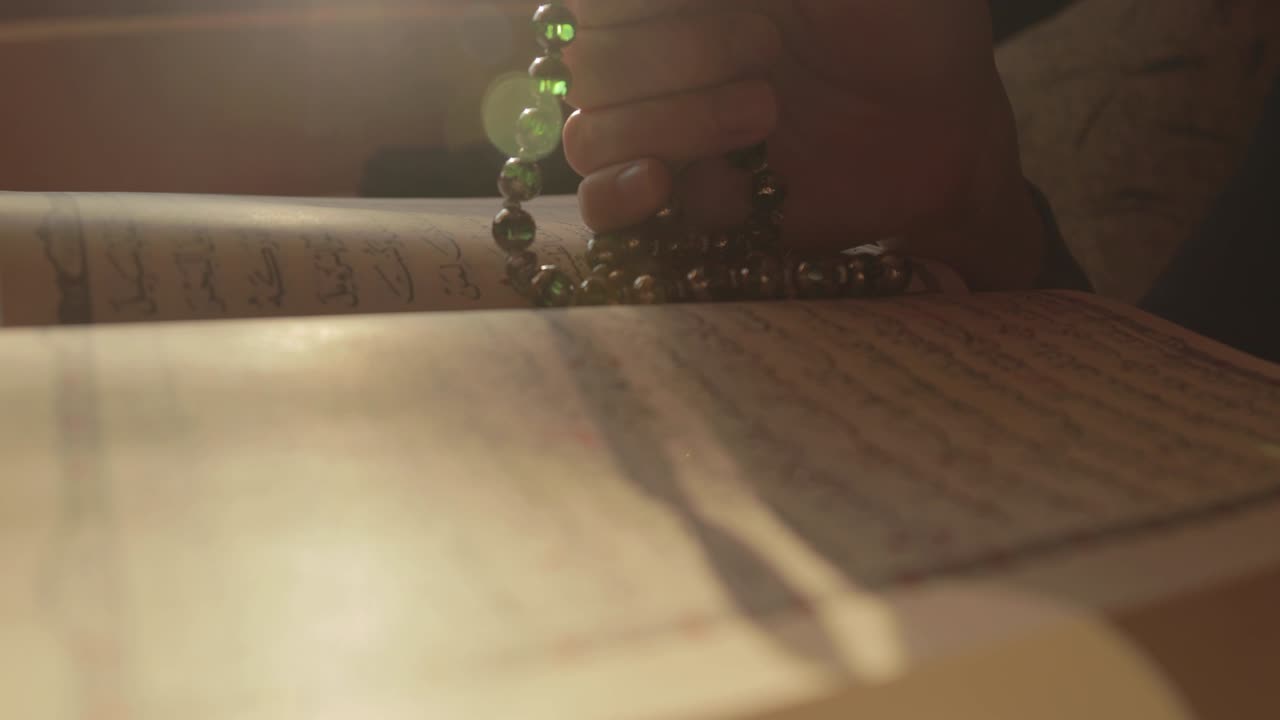 앞면 에 열려 있는 꾸란 을 가진 무슬림 기도 구슬 에 지크르 를 기도 하는 사람