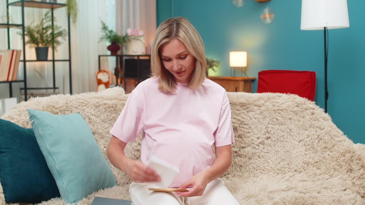 Pregnant woman writing future letter for baby placing envelope on belly smiling hopeful sweet hope