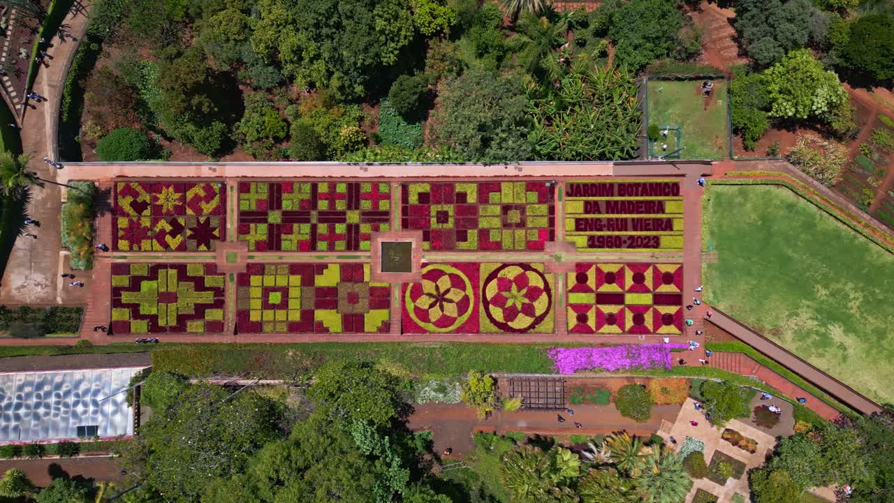 Birdseye aerial footage of the Madeira Botanical Garden in Funchal, showing geometric flower beds, vivid plant patterns and surrounding greenery. Ideal for travel, tourism and landscape themes