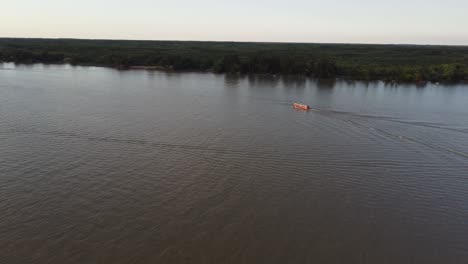 aerial view of cruising boat on parana river in argentina during golden hour