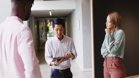 discussing project details, colleagues using tablet and standing in office hallway