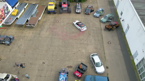 aerial view men filming a car drifting around in circle with marks of burnt rubber tires and smoke