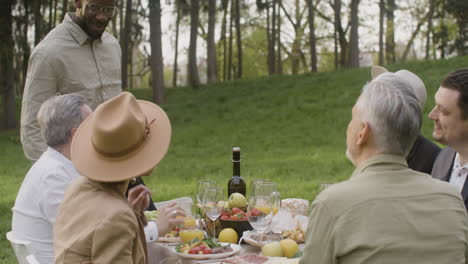 multirracial friends talking together while having a dinner in the park