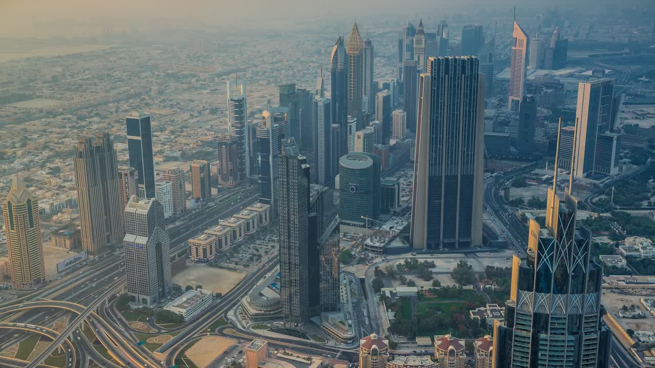 Dubai, Emirati Arabi Uniti: vista dalla cima del Burj Khalifa sulla città, che mostra grattacieli, un'autostrada con auto sottostanti e nuvole durante il giorno.