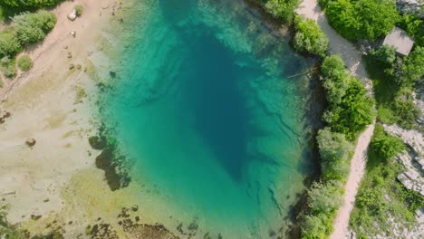 Rotación-Aérea-Y-Descenso-De-La-Fuente-De-Agua-Turquesa-Del-Río-Cetina,-Croacia