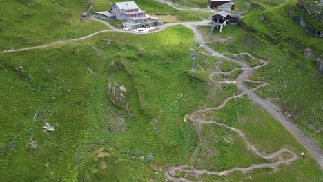 Drone-aerial-top-view-of-grass-fields-in-the-swiss-alps,-sinuous-biking-trail