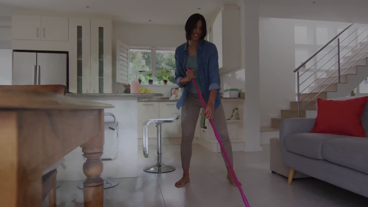 animación de nubes de humo sobre una mujer biracial feliz bailando mientras limpia el suelo en casa