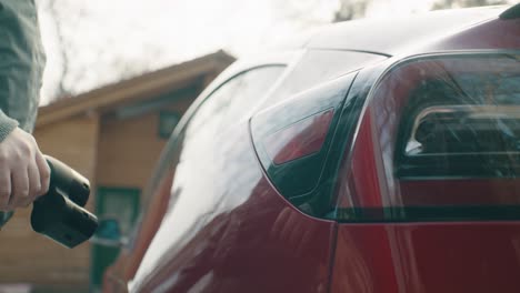close up of pulling out the charging cable and closing the car's charge port flap