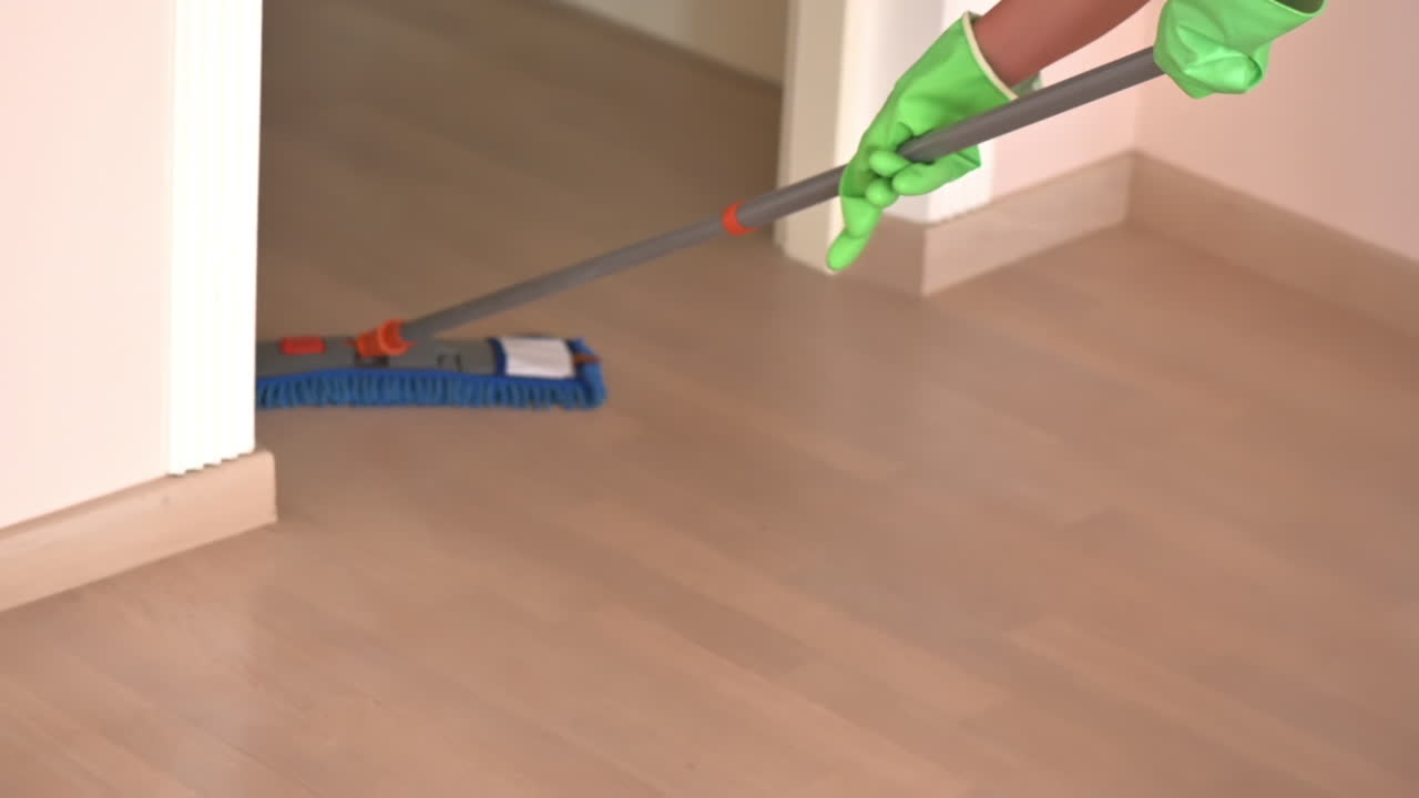 Close-up of a woman cleanind the floors with a blue mop
