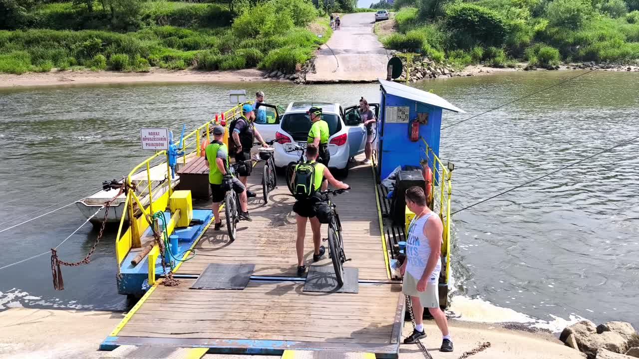 A Small Ferry Transporting a Car and Cyclists Across the Tisza River in Szeged, Hungary - Slow Motion