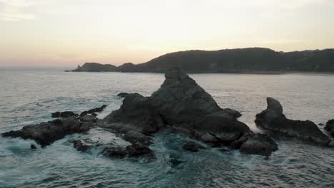 Vista-Aérea-Giratoria-Sobre-La-Roca-Que-Se-Forma-Sobre-El-Agua-Del-Mar-Con-Olas-Rompiendo-En-La-Costa-Del-Mar-Pacífico-En-Mazunte-En-El-Sur-De-México